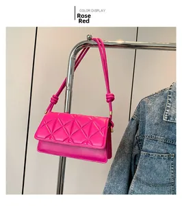 Detailed close-up of rose red quilted crossbody bag featuring elegant knot strap design