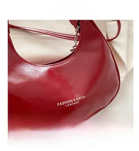 Detail of red crescent moon bag in pleated glossy leather with metal chain decoration