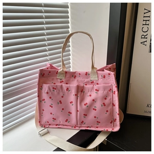 Detail of pink cherry print tote bag with two front pockets and adjustable strap