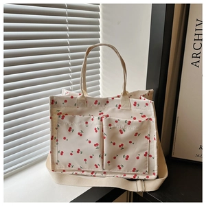 Close-up of cherry pattern canvas tote bag with front pockets and natural light shadows