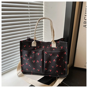 Detail of black cherry print canvas tote bag with front pockets and adjustable strap