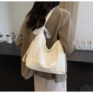 Détail d'un grand sac cabas crème avec un nœud en dentelle et le numéro 10 embossé