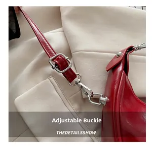 Macro shot of silver metal adjustment buckle on a red glossy leather crescent shoulder bag