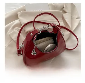 Detailed view of the red glossy crescent bag interior showing daily essentials and metallic charm