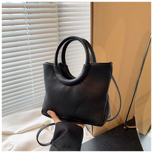 Detail view of the black lychee texture material and unique circular handle of the bag