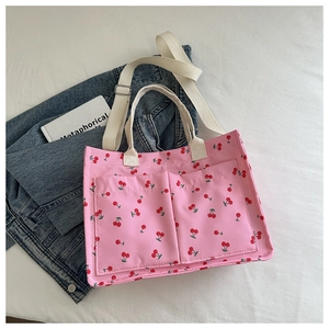 Detail view of pink canvas tote bag with cherry print featuring two large front pockets