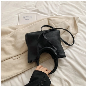 Detail of black lychee grain leather handbag with dual handles and soft texture