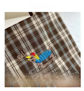 Détail du tissu à carreaux vintage avec broderie de chien et coutures en cuir marron
