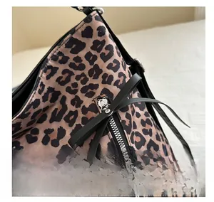 Detail of leopard print tote bag featuring a decorative black leather bow on zipper