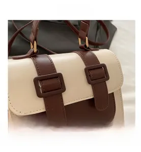 Detail of color-block flap bag with contrast straps and square metallic buckles