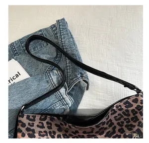 Detail of leopard print shoulder bag featuring black leather strap and silver metal buckle