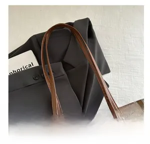 Gros plan sur un sac cabas à carreaux marron avec poignée en cuir et motif de style britannique