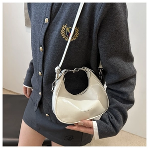 Detail of white patent leather crescent bag with mirror finish and metallic buckle