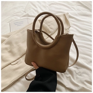 Detail view of mocha brown lychee grain leather handbag with circular handle and strap