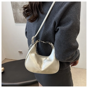 Silver metallic crescent bag worn over the shoulder with a grey knit sweater