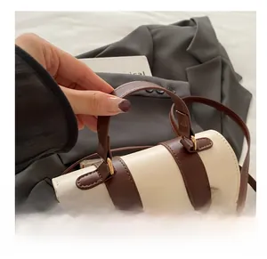Detail showing the chic two-tone cylindrical bucket bag with leather handles and strap