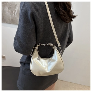 Detail of silver crescent shoulder bag with four-leaf clover charm and metal zipper