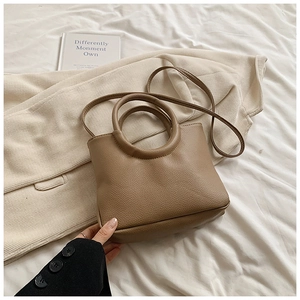 Detail of coffee brown litchi pattern leather bag with unique metal ring handle