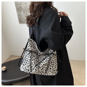 Detail of leopard print tote bag with metal zippers and decorative black bow on the side