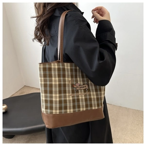 Détail du sac cabas vintage à carreaux avec garniture en cuir marron et broderie de chien