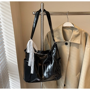Vue détaillée du sac cabas noir brillant avec motif M embossé et nœud décoratif en dentelle