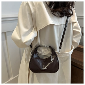 Detailed view of dark brown crescent bag with metal chain and decorative flower pendant
