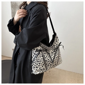 Close-up of leopard print tote bag with symmetrical zippers and bow detail