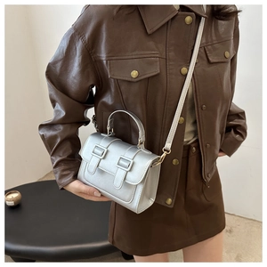 Chic silver metallic square bag styled with brown leather outfit in a modern setting