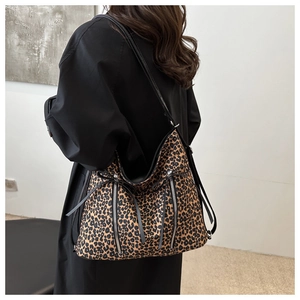 Close-up of leopard print shoulder bag with vertical zipper and fringe details