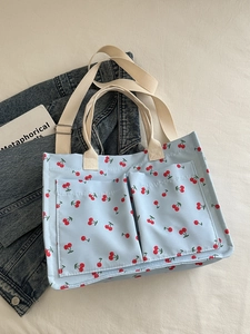 Large blue canvas tote bag with red cherry prints and dual front pockets for students