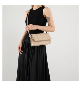 Detail of beige quilted crossbody bag with triangular stitching and knotted strap design