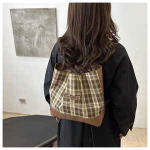 Détail d'un sac à dos vintage à carreaux marron avec broderie teckel sur modèle