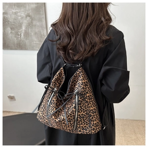 Detail of leopard print backpack with silver zipper accents and black strap closure