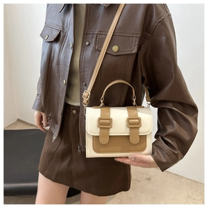 Detail of cream and brown contrast shoulder bag styled with a brown leather jacket