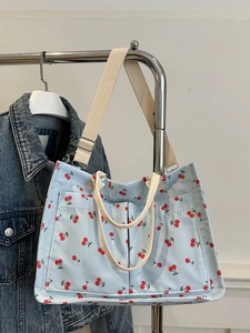 Blue canvas tote bag with cherry print, featuring front pockets and dual handles