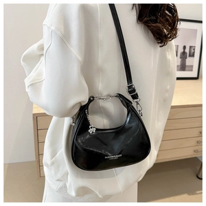 Detail of glossy black hobo bag with silver clover charm and adjustable leather strap