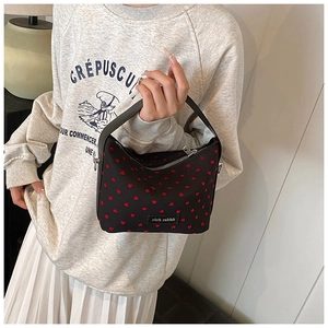 Détail d'un sac noir à motifs cœurs rouges avec étiquette en cuir de Rich Rabbit