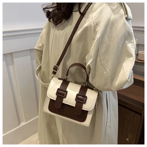 Side view of a vintage color-block crossbody bag in cream and dark brown on a model
