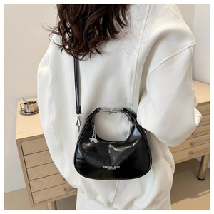 Back view of model wearing a black patent leather crescent bag with silver clover charm
