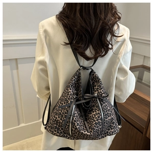 Detail view of leopard print backpack with silver zippers and black ribbon bows