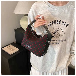 Détail d'un petit sac cabas noir avec motifs cœurs rouges et poignée en cuir élégante