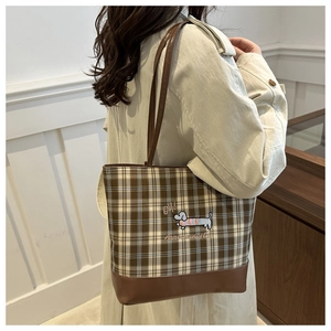 Détail du sac cabas à carreaux marron avec broderie teckel porté à l'épaule par un mannequin