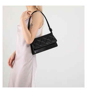 Detail of black quilted shoulder bag featuring unique geometric stitching and knotted strap