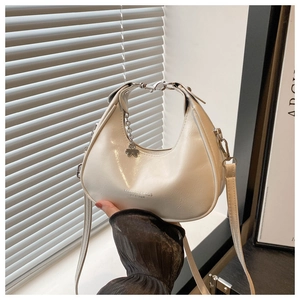 Detail of off-white crescent bag featuring a metallic clover charm and textured PU leather