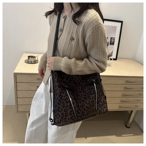 Detail of leopard print tote bag with silver zippers and black ribbon bows on shoulder