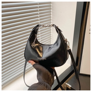 Detail of glossy black hobo bag with white leather text and metal chain decoration