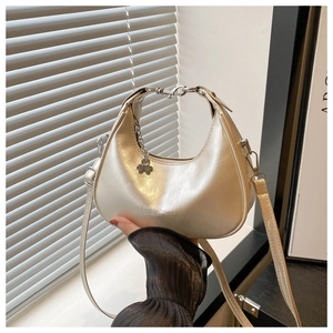 Detailed close-up of champagne crescent bag in crackled patent leather with silver chain