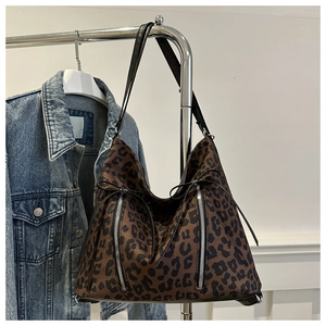 Detail shot of leopard print tote bag with vertical metal zippers and leather strap