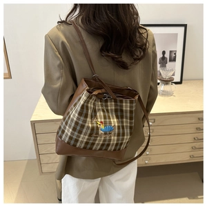 Détail du sac seau à carreaux avec broderie cartoon et bandoulière à cordon ajustable
