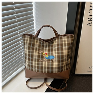 Détail d'un sac cabas à carreaux marron avec broderie de teckel et bandoulière en cuir